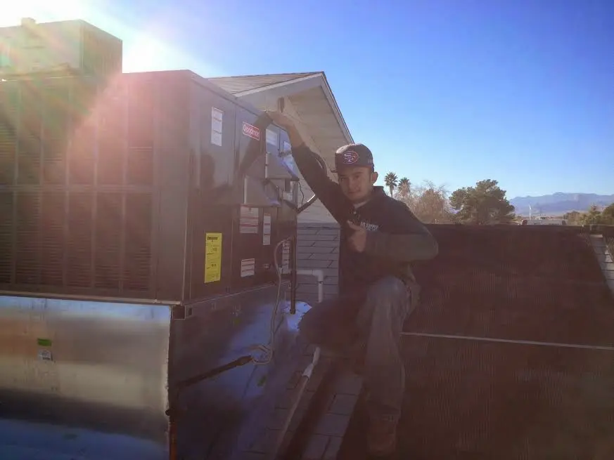 HVAC technician performing AC Tune-Up on a rooftop unit in Corcoran